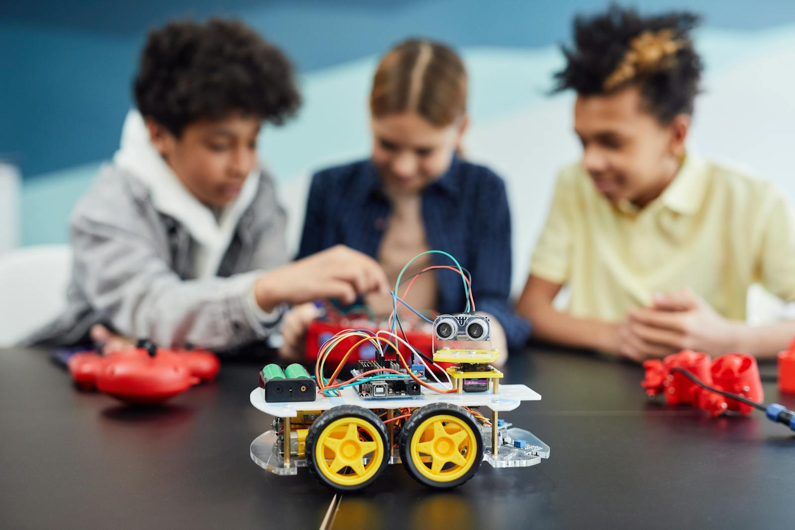 Children collaborating on a robotics project, building a small robot car in an educational setting.